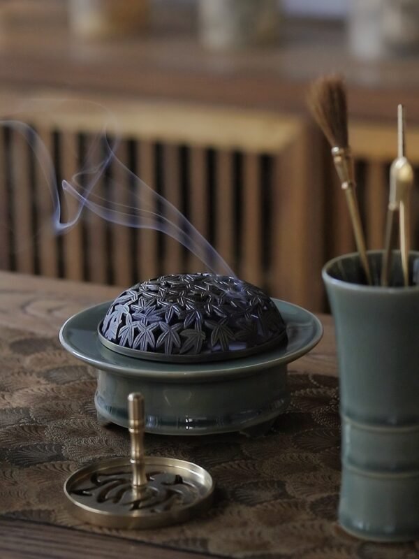 Yue Kiln Celadon Incense Burner, featuring a celadon incense burner emitting aromatic smoke, gold tools and a celadon vase, on a classically decorated wooden table.