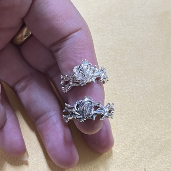 Two intricately designed silver rings on fingers.
