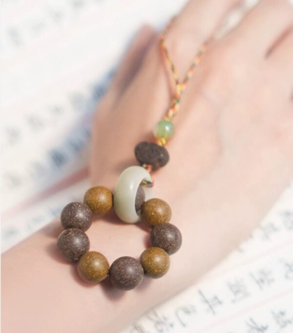 Hand with wooden bead bracelet and jade pendant