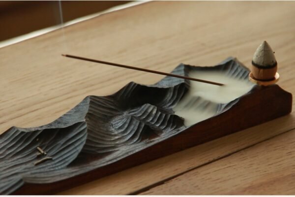 Incense burning on wooden holder with smoke.