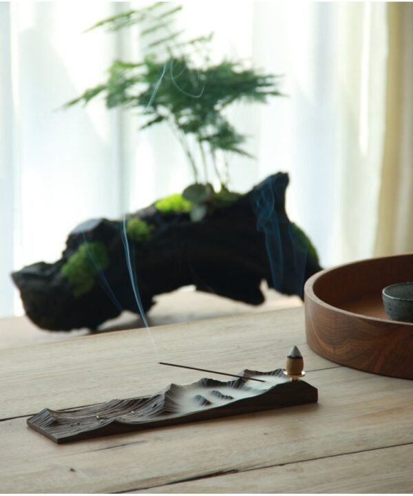 Incense burning with plant and wooden decor.