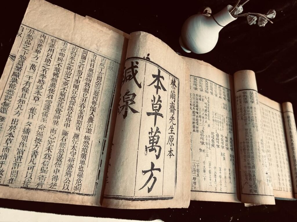 Ancient Chinese herbal medicine book "Bencao Wanfang" with traditional script and ceramic vase