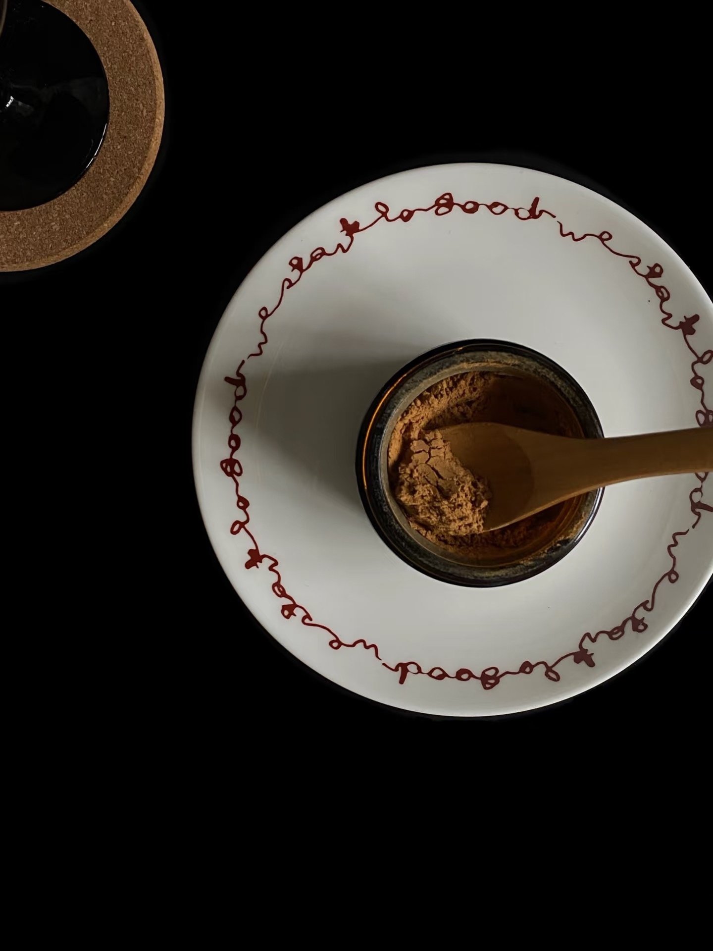 On the plate lies a jar of cinnamon powder with text on it and a wooden spoon - an ingredient in traditional Chinese medicine.
